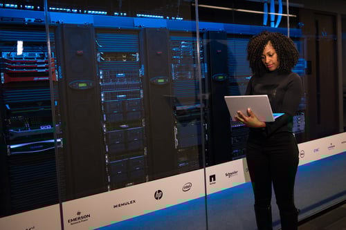 Woman standing next to server racks in a data center